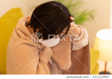 A middle-aged to senior woman suffering from fever in the living room on a winter night 121118467
