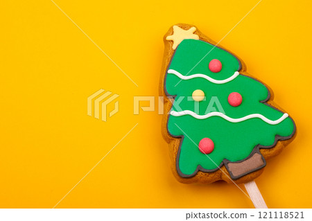 Christmas tree gingerbread cookie pop on yellow background Christmas tree gingerbread cookie pop on yellow background 121118521