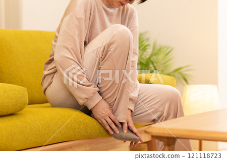 A middle-aged to senior woman suffering from cold feet in the living room on a winter night A middle-aged to senior woman suffering from cold feet in the living room on a winter night 121118723