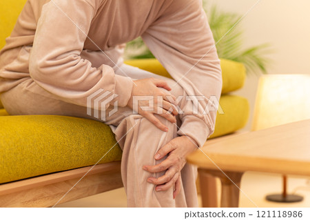 A middle-aged to senior woman suffering from cold feet in the living room on a winter night 121118986
