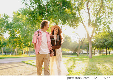 A Loving Couple Walking Together in a Beautiful Sunlit Park, Embracing Each Other Warmly A Loving Couple Walking Together in a Beautiful Sunlit Park, Embracing Each Other Warmly 121119756