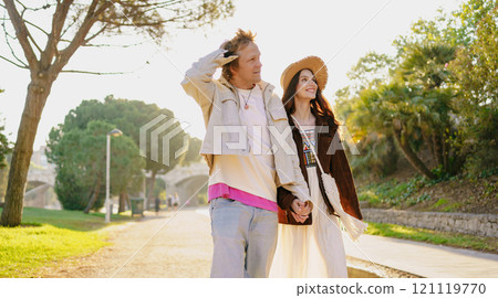 A couple is walking hand in hand, enjoying their time together in the beautiful nature A couple is walking hand in hand, enjoying their time together in the beautiful nature 121119770