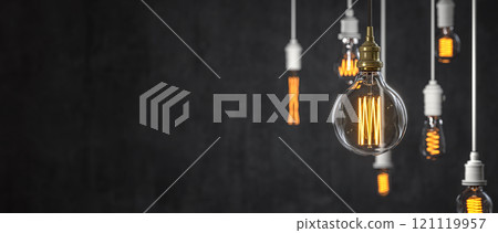 Hanging retro light bulbs illuminating a dark background 121119957