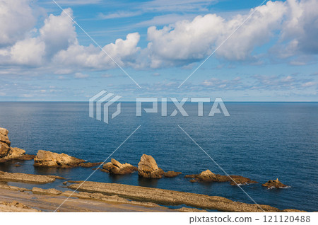 Calm ocean scene with unique coastal rock formations under a vibrant blue sky 121120488