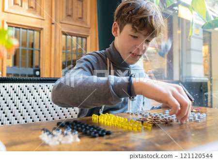 Teen boy playing with toy pieces 121120544