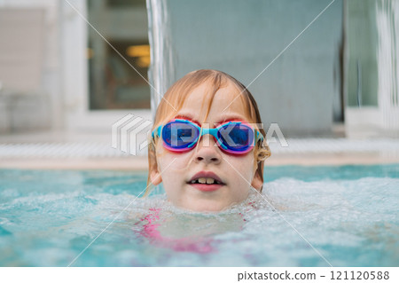 Girl in pool wearing goggles smiling Girl in pool wearing goggles smiling 121120588
