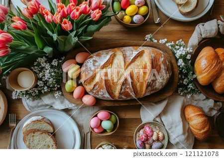 Easter table setting decorated with colorful eggs, bread, tulips and small white flowers Easter table setting decorated with colorful eggs, bread, tulips and small white flowers 121121078