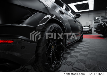 A close up view of a Lamborghini Urus Performante with a matte black finish in a showroom. The checkered floor and bright lighting highlight its design. 121121658