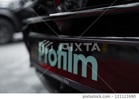 A close up view of the Profilm branding on a glossy car surface, with a blurred background hinting at a showroom or garage setting for luxury vehicles. A close up view of the Profilm branding on a glossy car surface, with a blurred background hinting at a showroom or garage setting for luxury vehicles. 121121690
