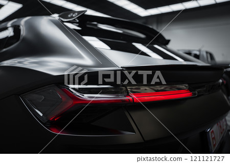 The image captures the rear section of a Lamborghini Urus Performante with matte black finish, showcasing its aerodynamic design and distinctive taillights indoors. 121121727