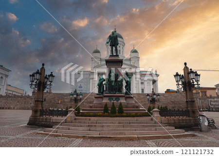 Helsinki Cathedral's neoclassical architecture with white facade and green domes is set against a sunset sky, featuring the Alexander II statue. Helsinki Cathedral's neoclassical architecture with white facade and green domes is set against a sunset sky, featuring the Alexander II statue. 121121732