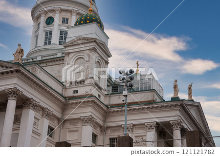 Helsinki Cathedral in Finland features grand columns, ornate statues, and a green dome with gold stars against a partly cloudy sky. Helsinki Cathedral in Finland features grand columns, ornate statues, and a green dome with gold stars against a partly cloudy sky. 121121782