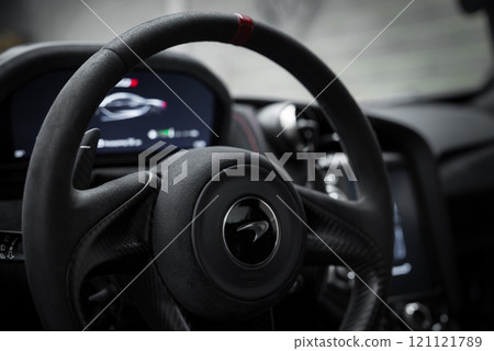 Interior view of McLaren 720S focusing on the steering wheel with red stripe and digital dashboard display, highlighting modern design elements. 121121789