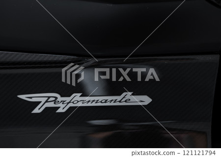 The image features a close up of the Performante badge on a Lamborghini Urus. The badge is set against a sleek, dark surface, highlighting its premium quality. 121121794