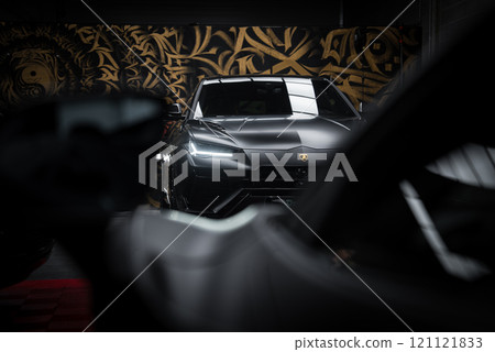 A Lamborghini Urus Performante is showcased indoors, highlighting its sleek design and distinctive headlights against gold and black wall art. 121121833