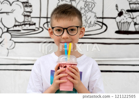 The child drinks a cocktail through a straw and smiles 121122505