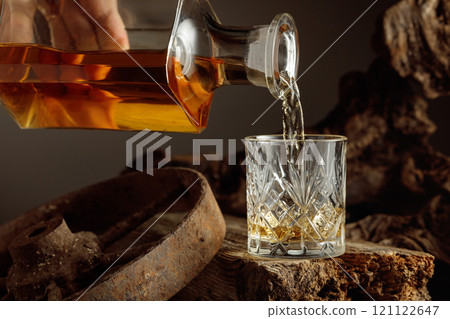 Whiskey is poured from a decanter into a glass. 121122647
