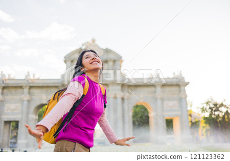 Happy latin american student enjoying her trip to puerta de alcala in madrid, spain 121123362
