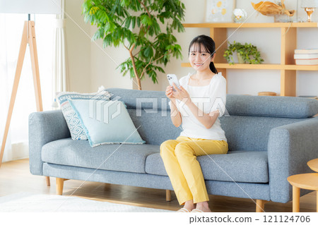 A young woman operating a smartphone in a room A young woman operating a smartphone in a room 121124706