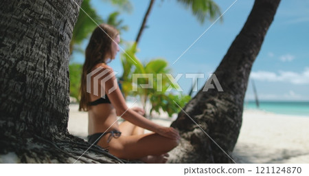 Woman relaxing on tropical beach sitting under palm tree. Long hair slim brunette girl in bikini tan on White Beach, Boracay Island, Philippines. Travel, tourism, holiday. Summer landscape. Slo Mo 121124870