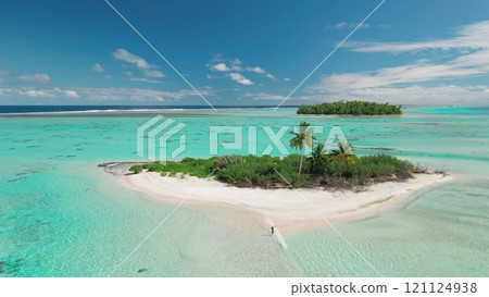 Aerial view of a woman enjoying a tropical paradise as she walks on a sandbank that connects a small island to a larger one Aerial view of a woman enjoying a tropical paradise as she walks on a sandbank that connects a small island to a larger one 121124938