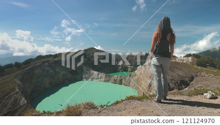 Tourist woman enjoy morning view on volcanic Kelimutu blue crater lakes. Nature background. Travel destination. Beautiful wild landscape. Exotic summer vacation, hiking, relax. Close up back view 121124970