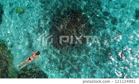 Woman swimming in crystal water exploring coral reef underwater sea life Slim tourist female snorkeling with mask. Travel, tourism, holiday, relax, summer lifestyle . Aerial top down view, drone shot 121124981