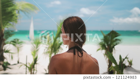 A woman stands on the sandy shore of Boracay Islands White Beach, gazing out at the vast ocean ahead of her. 121124983