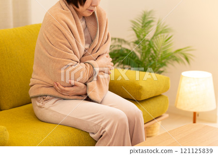 Middle-aged to senior women feeling cold in the living room on a winter night 121125839