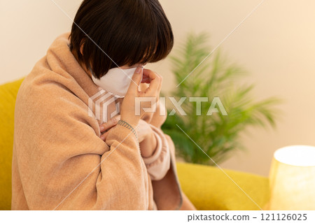 A middle-aged to senior woman holding her nose in the living room on a winter night 121126025