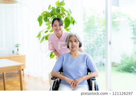 Caregiver supporting a woman in a wheelchair 121126297