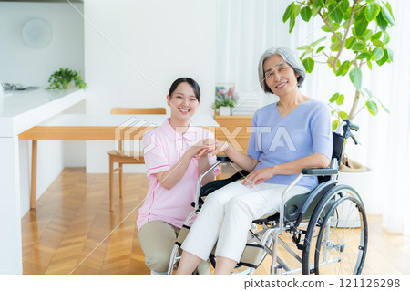 Caregiver supporting a woman in a wheelchair 121126298