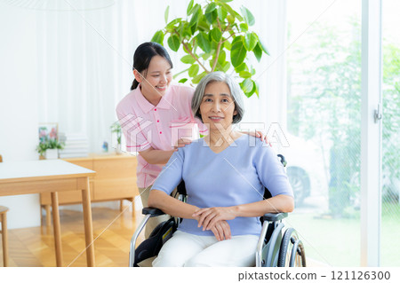 Caregiver supporting a woman in a wheelchair Caregiver supporting a woman in a wheelchair 121126300