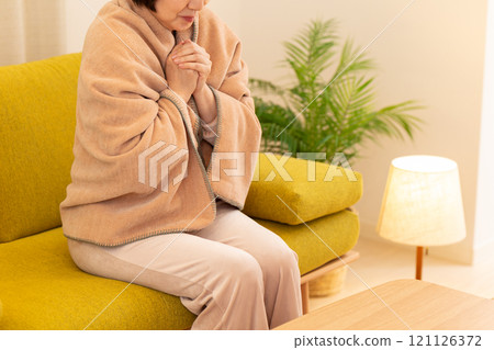 Middle-aged to senior women feeling cold in the living room on a winter night Middle-aged to senior women feeling cold in the living room on a winter night 121126372