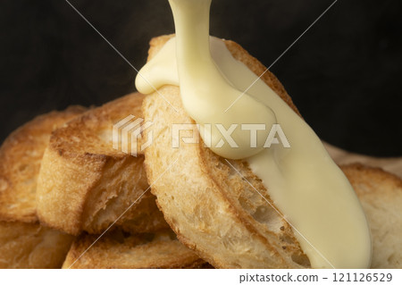 Spread melted cheese on baguette 121126529