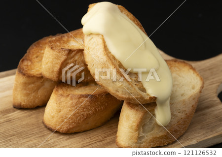 Spread melted cheese on baguette 121126532