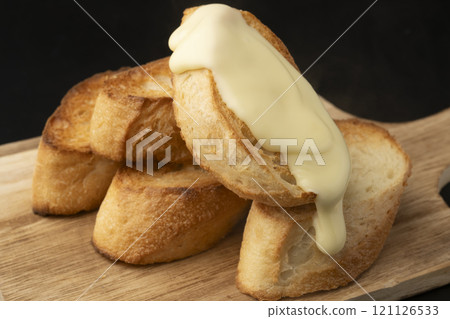Spread melted cheese on baguette 121126533