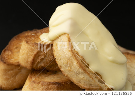 Spread melted cheese on baguette 121126536