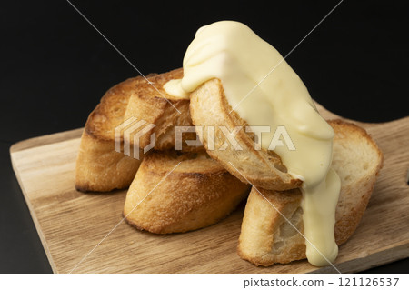 Spread melted cheese on baguette 121126537