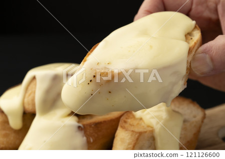 Holding up a baguette topped with cheese 121126600