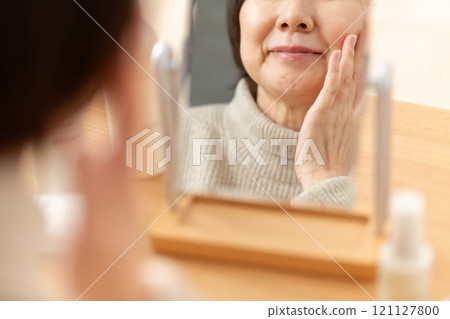 中高級女性在鏡子前使用基本化妝品進行皮膚護理 121127800