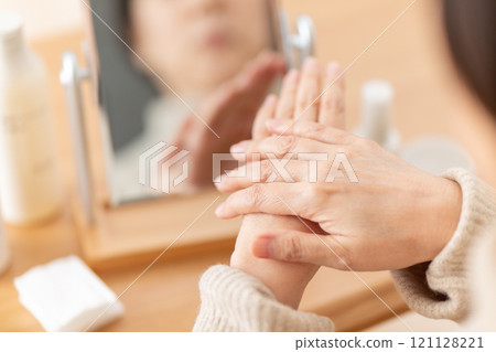 中年婦女在鏡子前進行手部皮膚護理 中年婦女在鏡子前進行手部皮膚護理 121128221