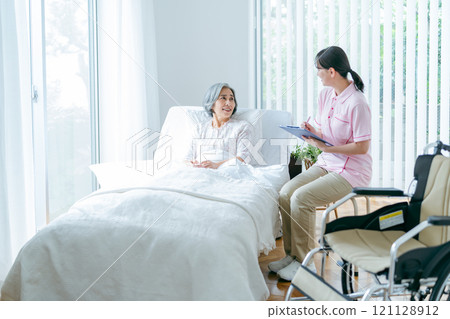 Senior woman living in a nursing home and a young helper Senior woman living in a nursing home and a young helper 121128912