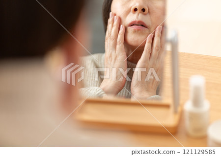 中高級女性在鏡子前使用基本化妝品進行皮膚護理 121129585