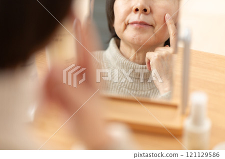 中高級女性在鏡子前使用基本化妝品進行皮膚護理 121129586