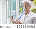 Asian senior patient exercising her lungs,using incentive spirometer,measuring the air capacity of the lungs,old elderly with emphysema,problem of respiratory disease,therapy,treatment,health care 121130408