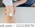 Arm of woman with bruise on foldable joint from needle,plaster and cotton to cover wound,fragile vein,broken capillary blood vessels under skin,painful after blood test,medical checkup,blood donation 121130570