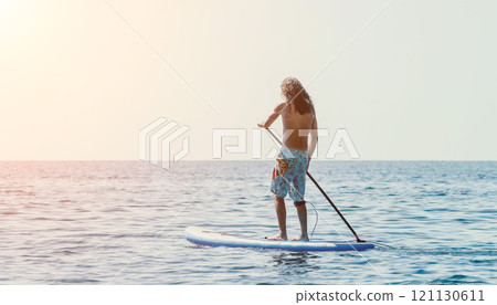 Man Paddleboarding Ocean Water Sports Sunset - A man paddleboards on the ocean at sunset. Man Paddleboarding Ocean Water Sports Sunset - A man paddleboards on the ocean at sunset. 121130611