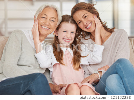 Family generations of females sitting together and looking at the camera. Portrait of an adorable little girl bonding with her mother and grandmother at home. Enjoying a visit with her granddaughter 121132228