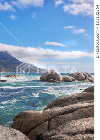 Landscape view of sea water, rocks and a blue sky with copy space in Camps Bay Beach, Cape Town, South Africa. Calm, serene, tranquil, ocean and relaxing nature scenery. Waves washing on rocky shore 121132254